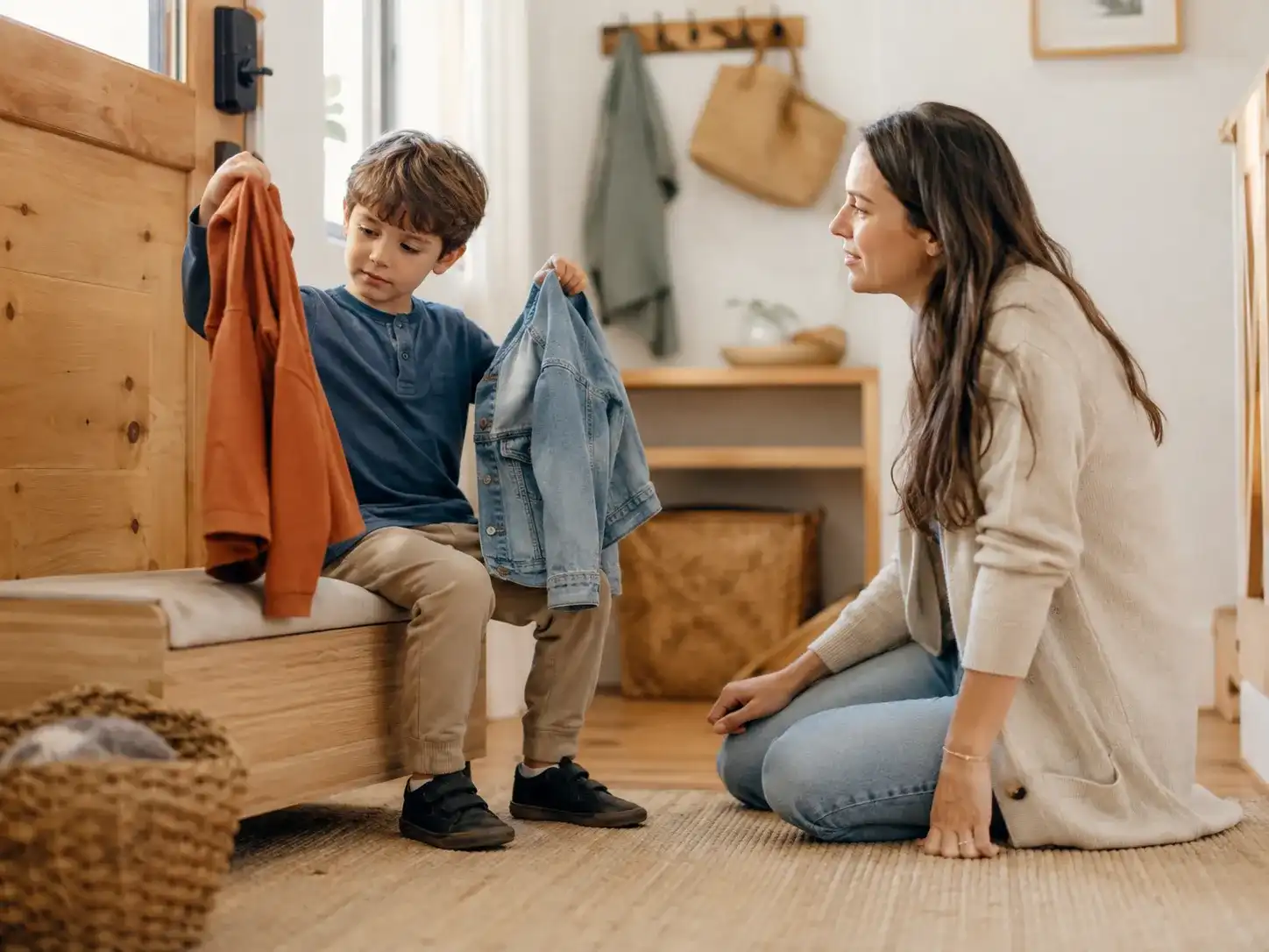 A child choosing between two clothing options while a parent waits supportively nearby